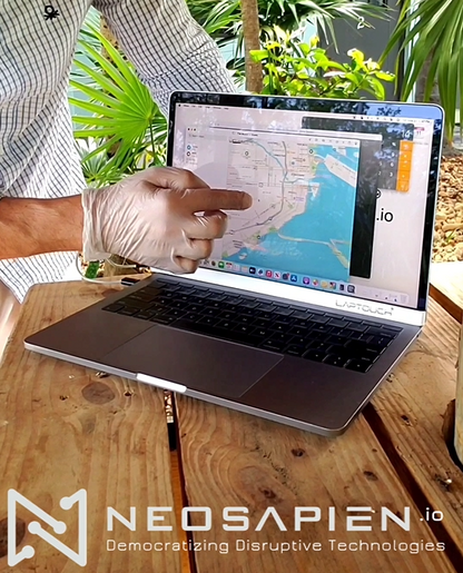 Even works with gloves! Person using a laptop with a map on the screen, wearing gloves, on a wooden table with plants in the background. NEOSAPIEN.